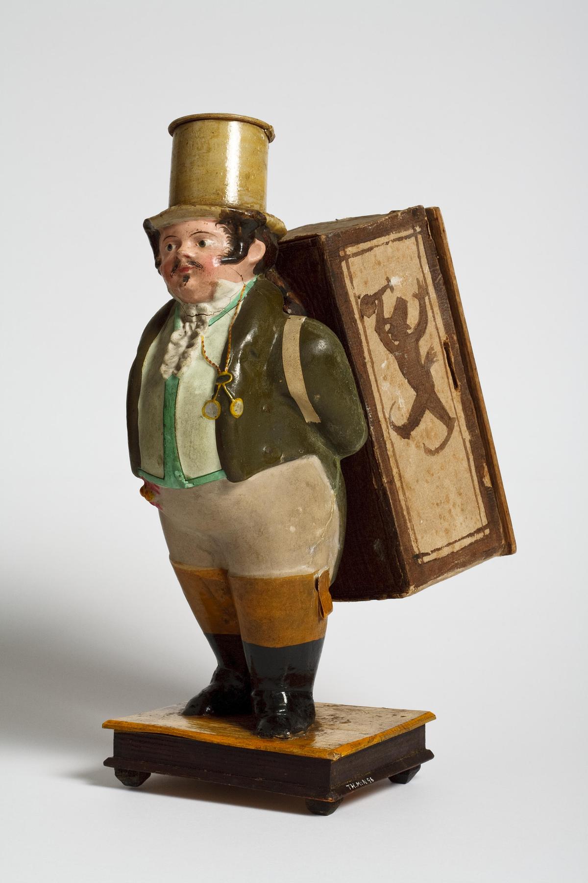Mandlig figur med en kasse på ryggen. Indeni kassen en papirrulle der viser  kunstnere i et optog, N96 - Thorvaldsens Museums Katalog