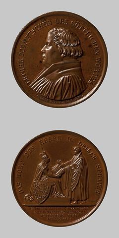 F91 Medaljens forside: Martin Luther. Medaljens bagside: Martin Luther overrækker Germania sin tyske Bibeloversættelse