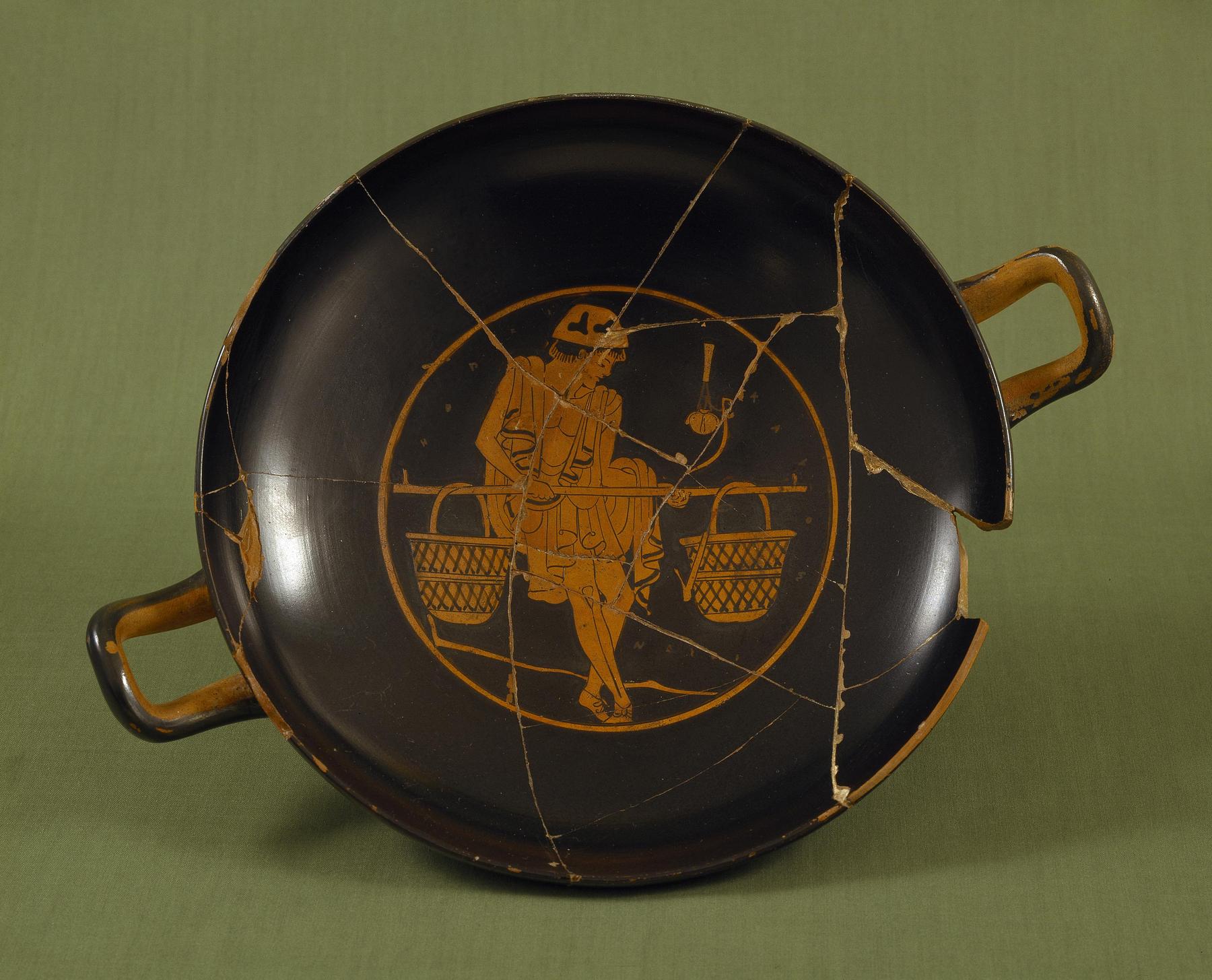 Kylix with a youth carrying a pole with two baskets, H605
